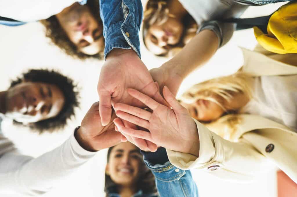 Hands of a multi-ethnic group of friends joined together as a sign of support and teamwork