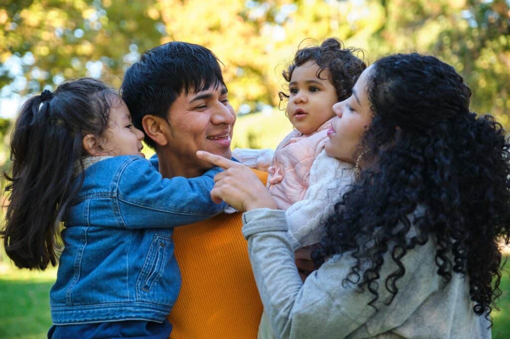 Familia latina feliz con dos hijos juntos en un parque.